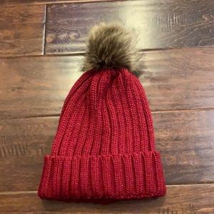 Knit maroonish red beanie with faux fur pom pom